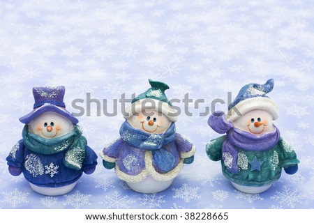 Three snowman sitting together on a snowflake background, happy holidays