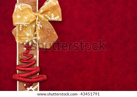 A gold ribbon bow sitting with a snowflake ribbon on a red background