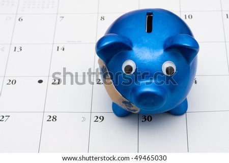 A blue piggy bank with adhesive bandage on a calendar, Are you hurting paying your bills