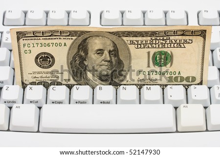 One hundred dollar bills sitting on a computer keyboard, making money online