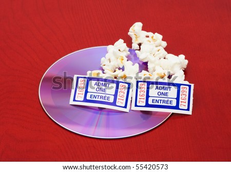 A few kernels of popcorn with a dvd and tickets on a wood background, movie and popcorn