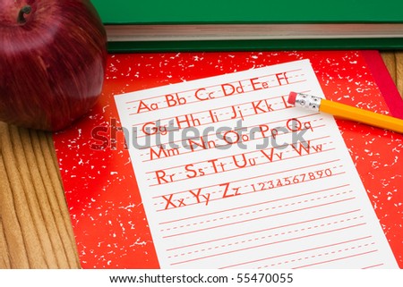 A pencil on a workbook with an apple and a book, school work