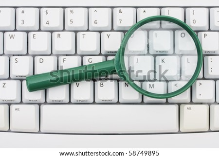 A green magnify glass on a computer keyboard, Searching on the internet
