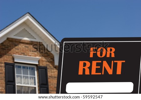 A black and orange for rent sign with a brick house in background