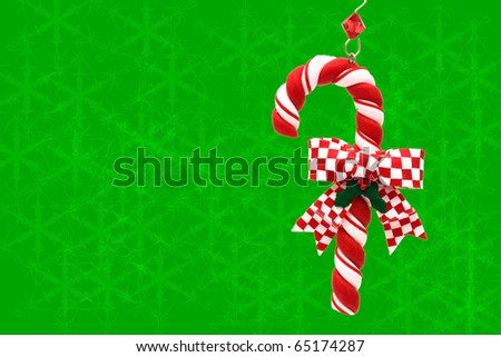 A candy cane hanging on a green snowflake background, Christmas Time