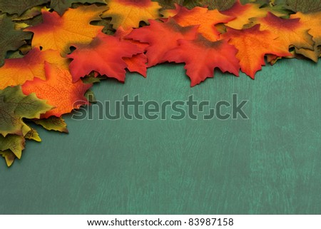 Green, orange, red leaves with some changing colors border over green grunge background, The changing of the seasons