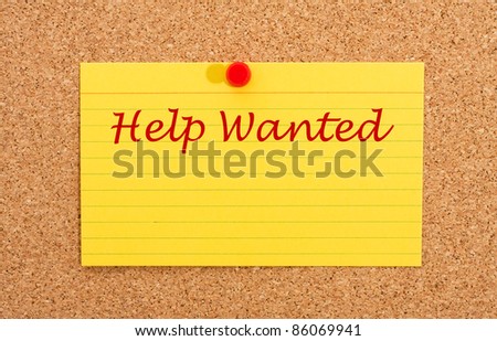 A yellow index card on a cork board with the words help wanted on it