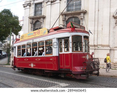 LISBON, PORTUGAL - SEPTEMBER 21, 2014: Unidentified tourists ride an old tram in front of Saint Anthony Church. Old trams are among the main tourist attractions of the city.