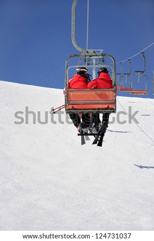 Skiers couple on a ski lift in red skisuit
