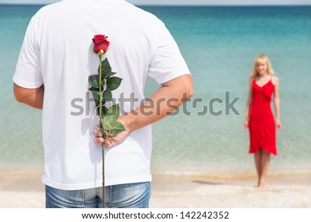 loving couple - man with rose waiting his woman on the sea beach at summer - the romantic date or wedding or valentines day concept
