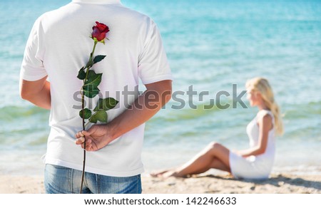 loving couple - man with rose waiting his woman on the sea beach at summer - the romantic date or wedding or valentines day concept
