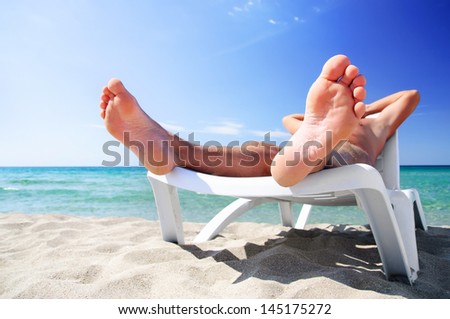 Young man in white cap sunbathe on beach bed at summer sea beach
