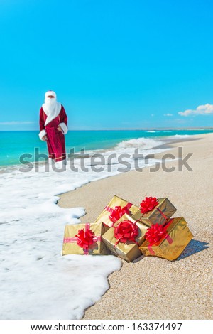 Santa Claus with many golden gifts relaxing on sandy sea beach - christmas or happy new year concept