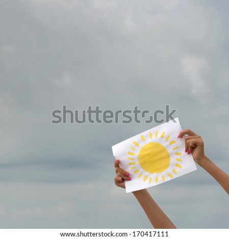 human hands with sheet of paper with sun image against overcast sky - positive thinking concept