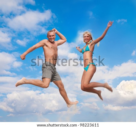 young people - man and woman - jumping in the air against a blue sky