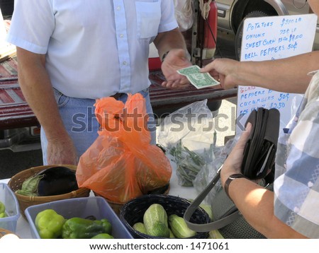 Vendor at farmers market receives cash to add to the wad already in pocket.