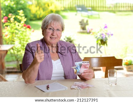 older woman with money and thumb up