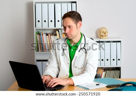 young family doctor in his office is working with the computer