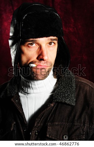 man with cigarette and coat cap