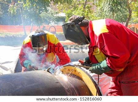 Welders welding pipes, teamwork