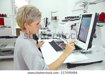 Woman working on computerized machine embroidery