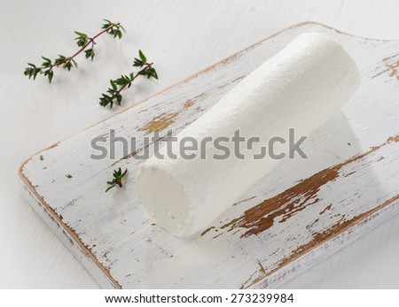 Goat cheese with fresh herbs on  white wooden table.