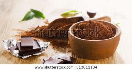 Chocolate bars and bowl of cacao powder. Selective focus