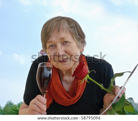 Happy senior woman with red wine and flowers