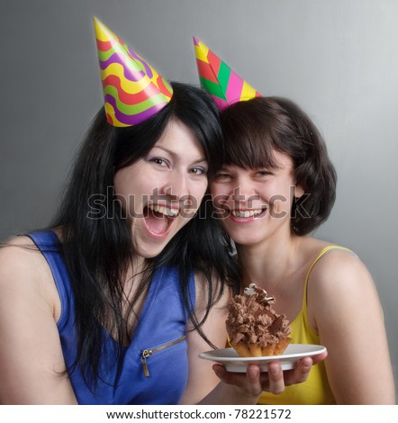 Two happy young women with cake