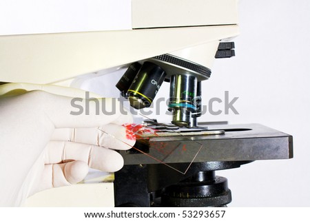 Hand with latex examination glove placing blood sample under microscope in  laboratory isolated over white background medical research concept
