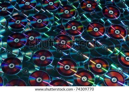 A background of DVD CD CD-ROM discs with reflective array lighting. Contrasting disc colors make a stunning technological backdrop.