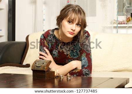 Sad girl sitting in front of a column of coins