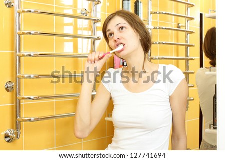 A girl in a white shirt and shorts, brushing his teeth in the bath