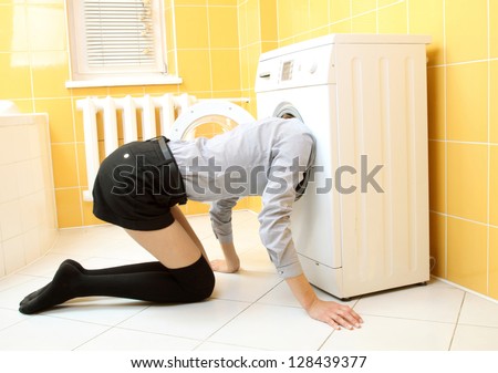 Ordinary simple beautiful girl put her head into a washing machine