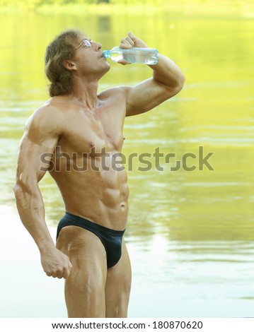 Male fitness model drinking water from a bottle