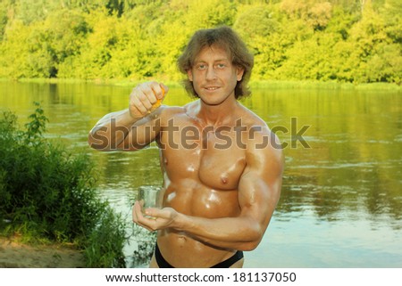 male fitness model bodybuilder squeezes out orange juice in a glass