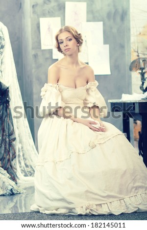 Beautiful woman in vintage dress is in clothing design studio