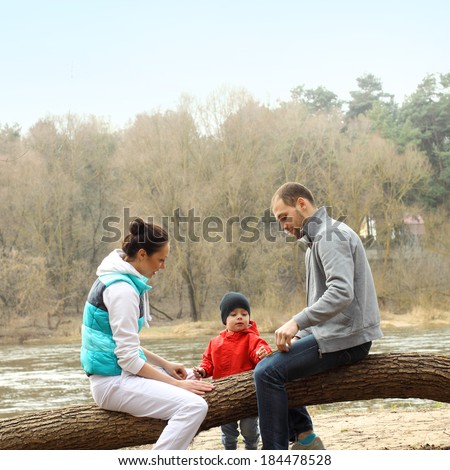 Young family sitting on a tree near the river
