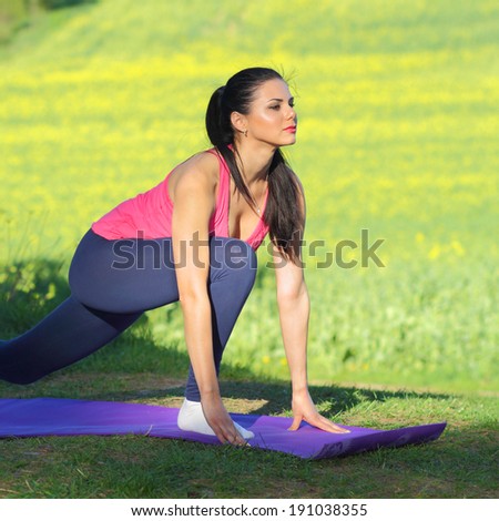 Beautiful woman practices yoga in nature against the yellow field