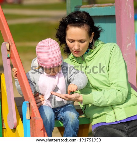 young mother playing with child on the playground outdoors. Mother and daughter playing on the playground outdoors on a sunny day