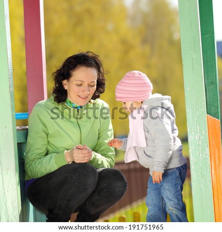 young mother playing with child on the playground outdoors. Mother and daughter playing on the playground outdoors on a sunny day