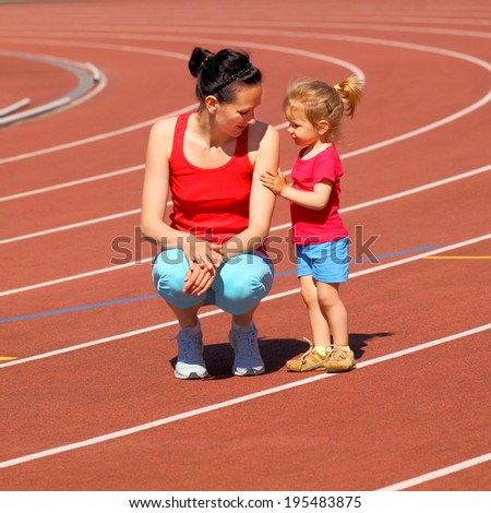 Mother & little daughter running around the stadium. young mother sat down and talking with the child at the stadium.
