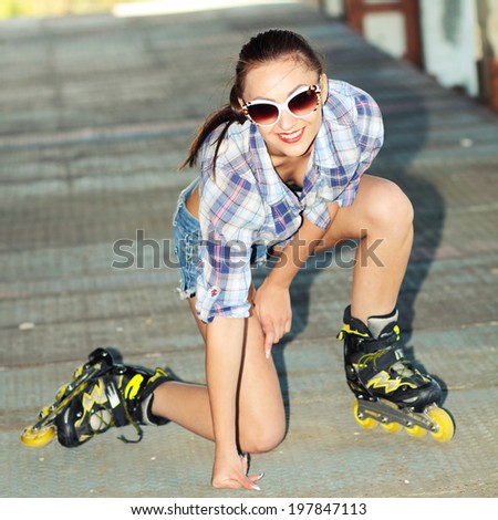 beautiful fashionable girl in white sunglasses on roller skates. attractive girl in the garage with roller skates