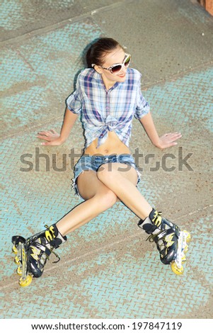beautiful fashionable girl in white sunglasses on roller skates. attractive girl in the garage with roller skates