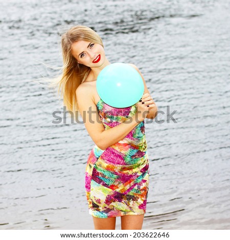 Happy young woman having fun with colorful latex balloon on water background.
