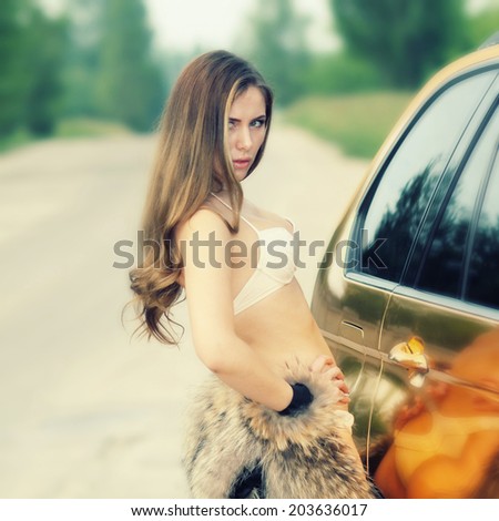Beautiful sexy girl in bikini and in fur cape posing on a background of golden car. sexy lady near the golden car. in vintage colors.