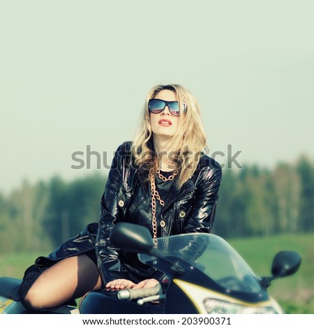 Portrait of a beautiful blonde woman in sunglasses on a sports motorcycle. Urban life style.