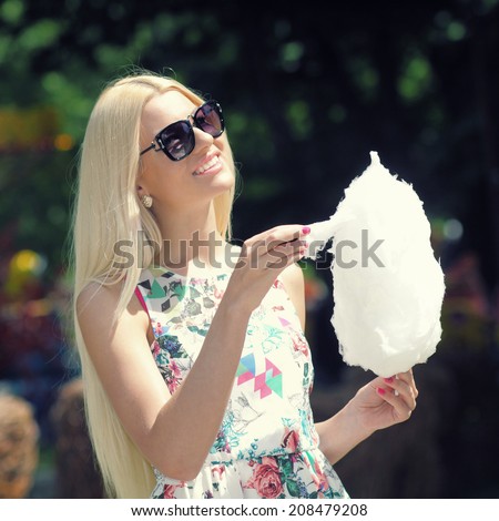 summer trendy girl in sunglasses having fun in the park and eating candy floss. Outdoors. Urban lifestyle shot.