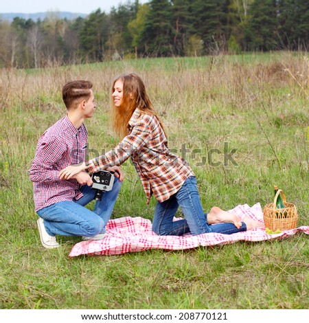 young hipster guy photographs the girl on a vintage camera. Young hipster couple on a picnic