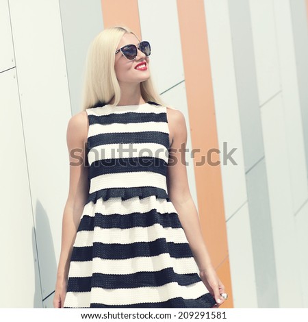 Portrait of trendy fashion girl in sunglasses on the background color of orange wall